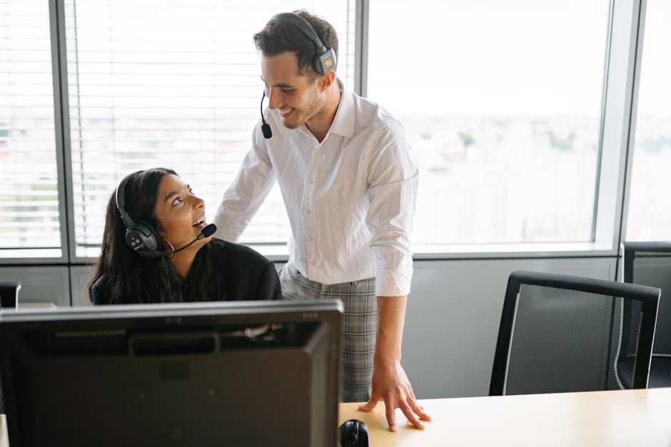 Smiling colleagues wearing headsets working together at a call center in a modern office setting.